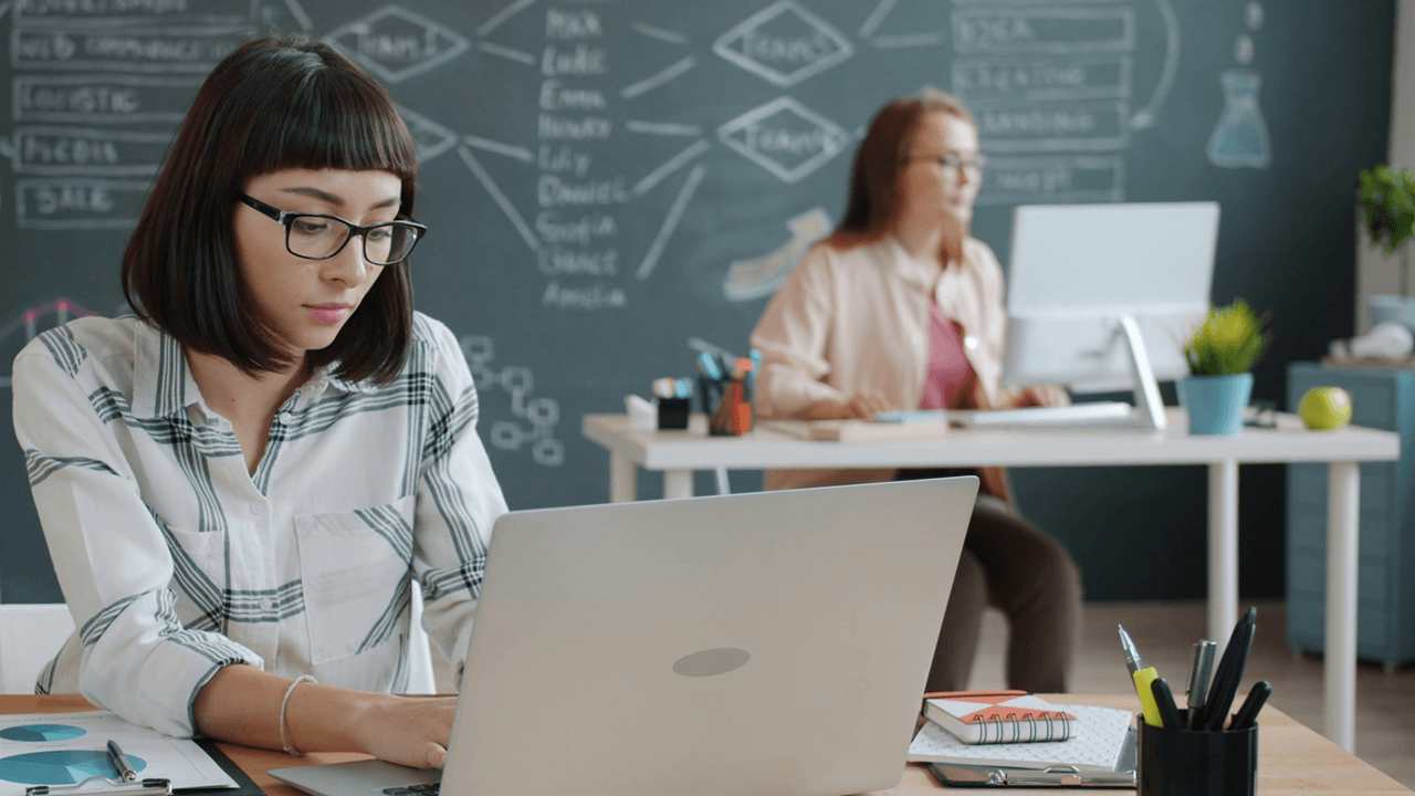 2 women working at computers at desks in an office