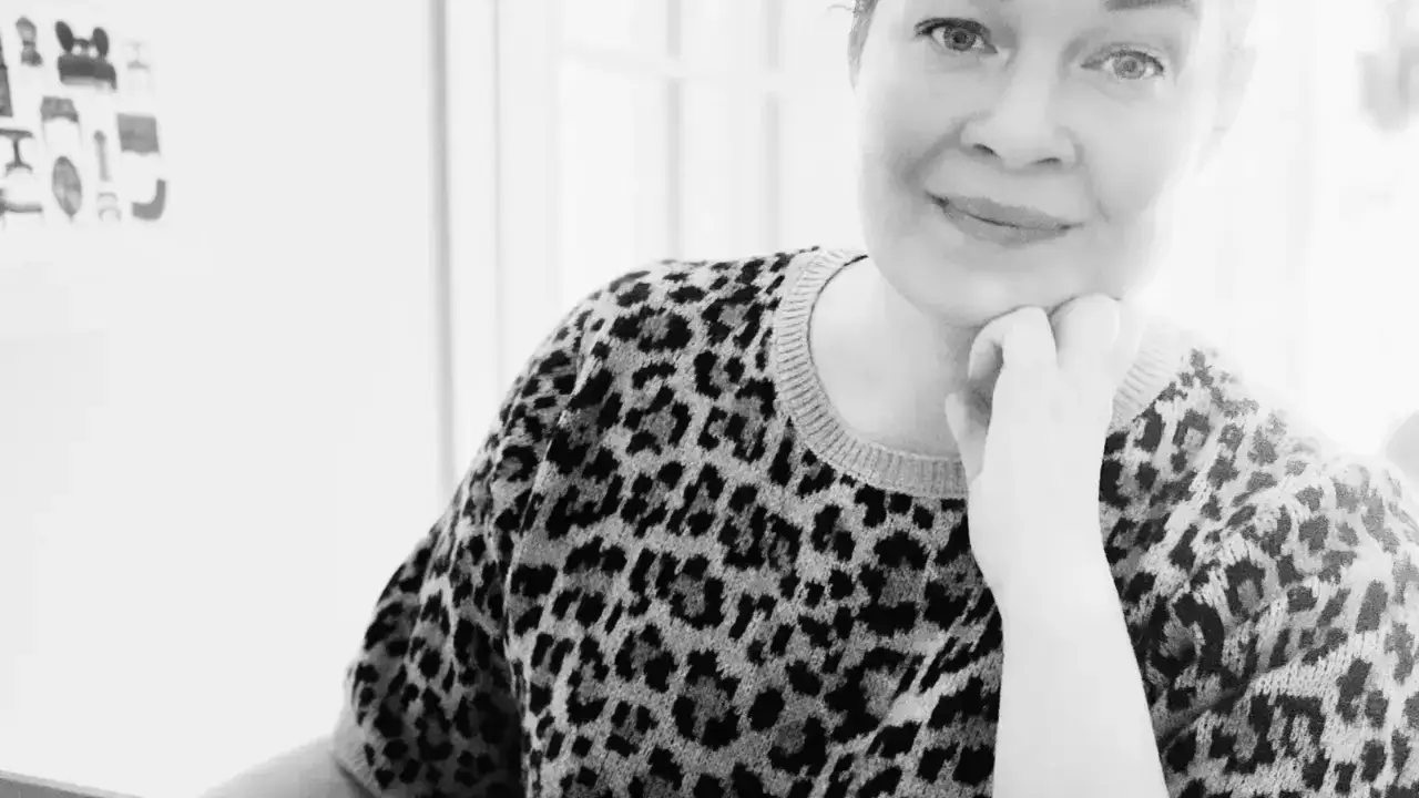 Sandra Törnroth smiling, chin resting on her hand, in a leopard print sweater