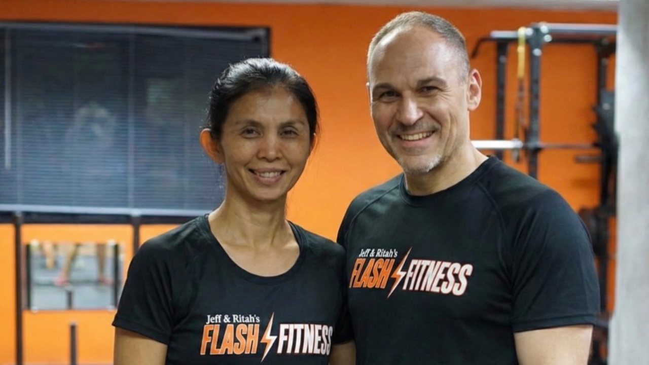 Jeff Andora and Ritah, owners and elite fitness coaches at Flash Fitness Bangkok in Sathorn, standing inside their results-driven personal training gym.