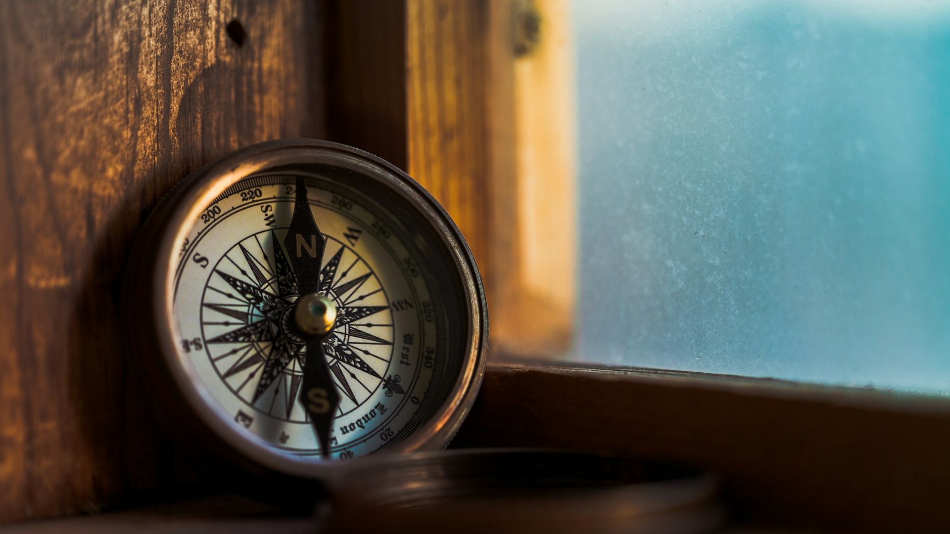 Compass leaning against wooden windowsill.