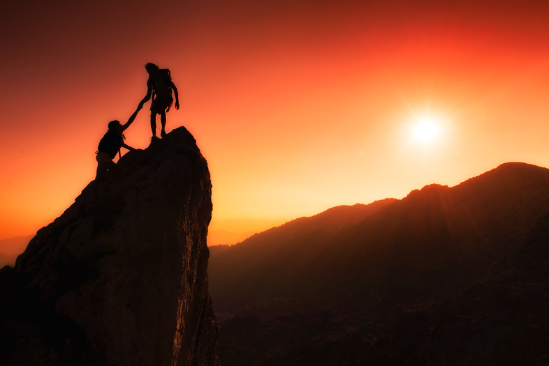 Climbers helping each other up a rock face