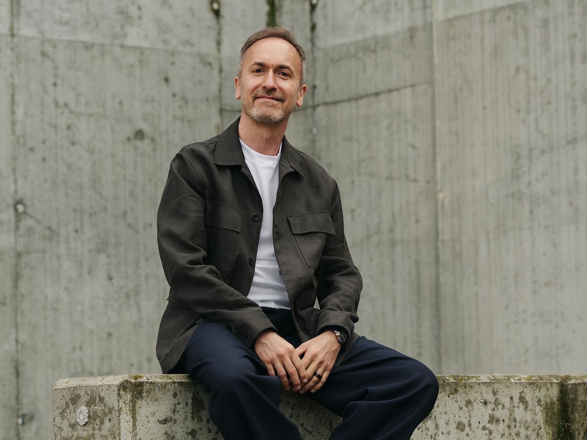 Piotr Mechlinski, seated against a concrete wall, looking to camera.