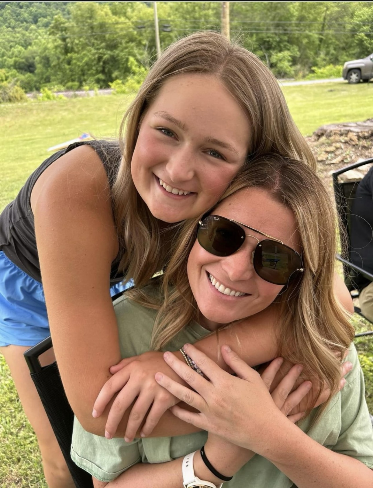 Jess smiling while her daughter hugs her from behind