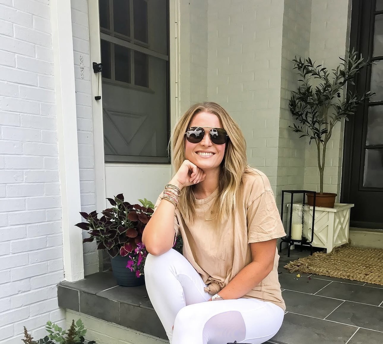 Jess smiling on her front steps in sunglasses