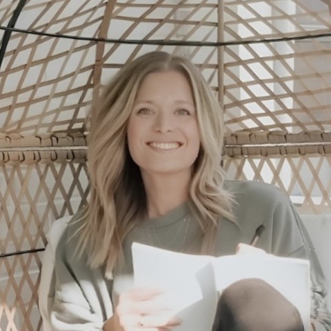 Jess Winkler smiling in a wicker egg chair