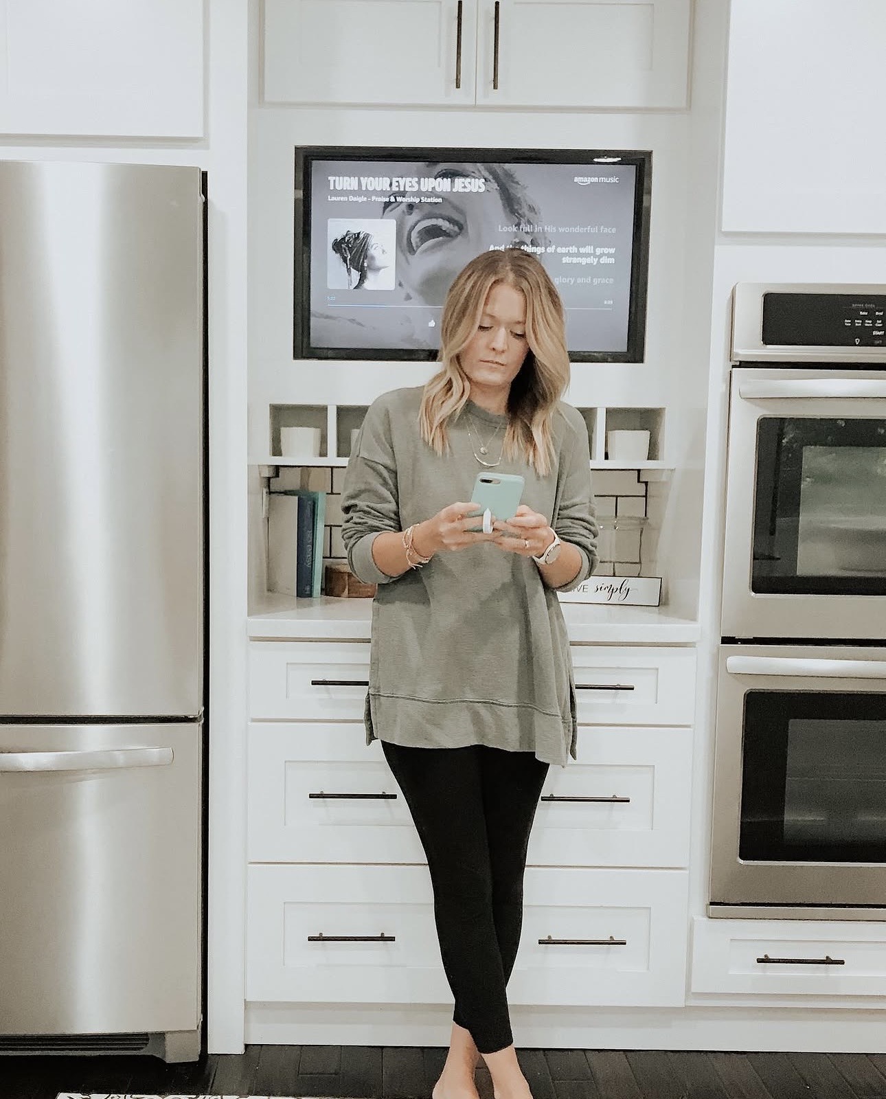 Jess standing in her kitchen, checking her phone