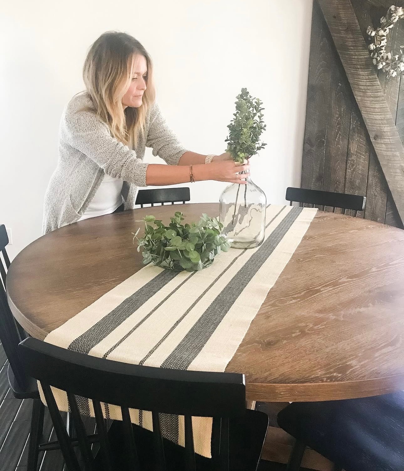 Jess arranging greenery in a vase on her dining table