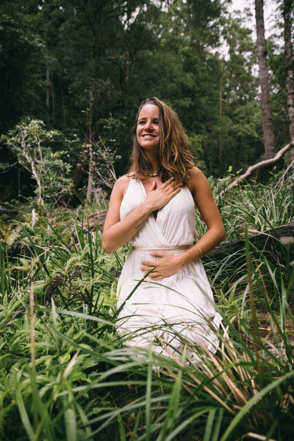 Sophie Saemrow resting a hand on her heart among green ferns.