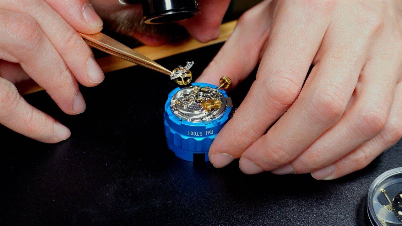 Mains au travail avec brucelles sur un mouvement de montre — méthode pratique de la formation