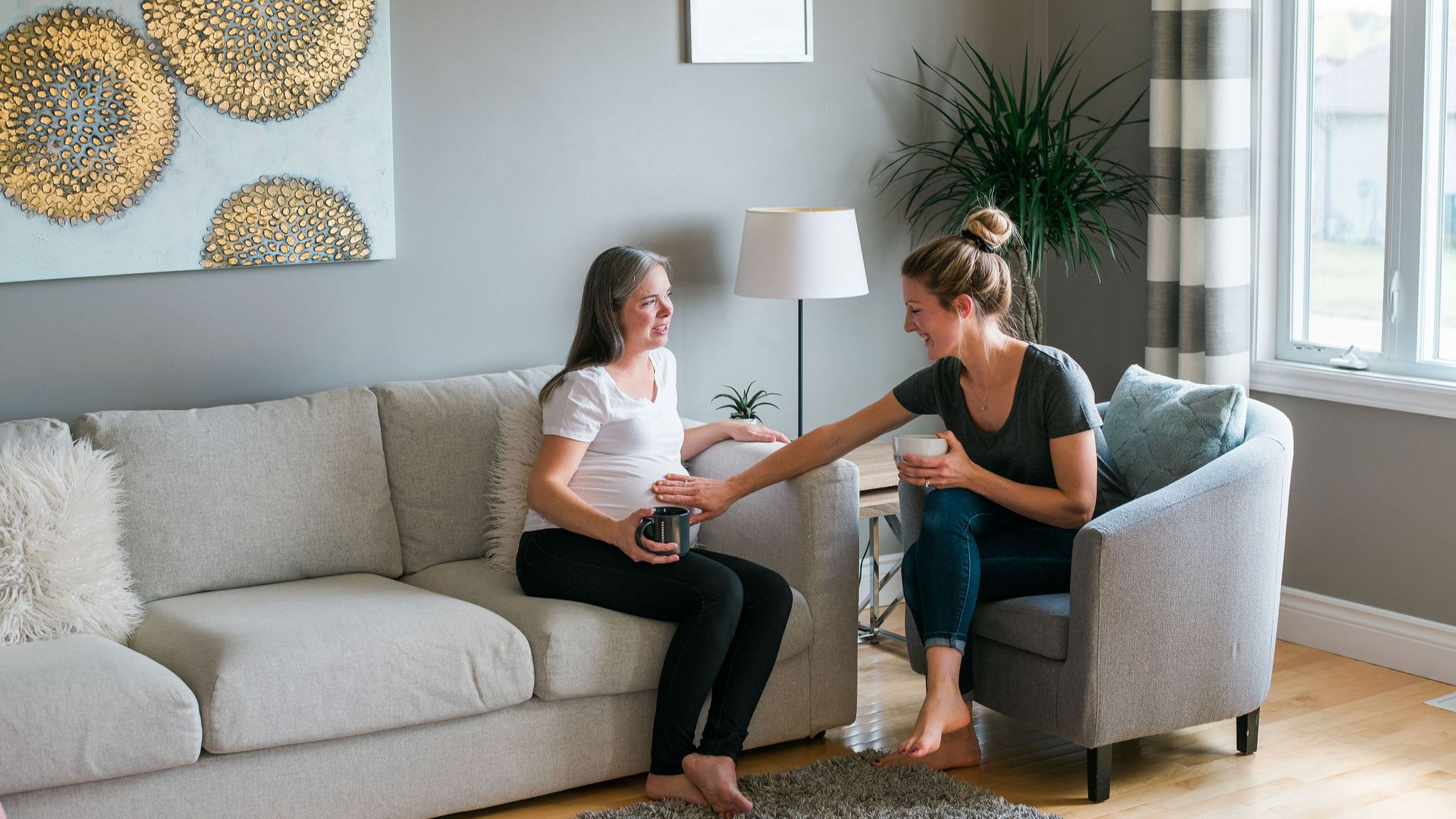 Pregnant woman and doula sitting together drinking tea
