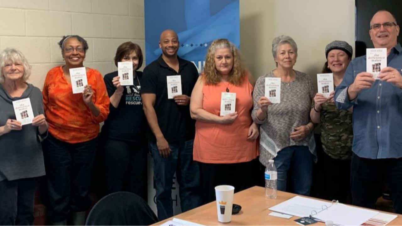 A group of people holding copies of The Difference Maker book