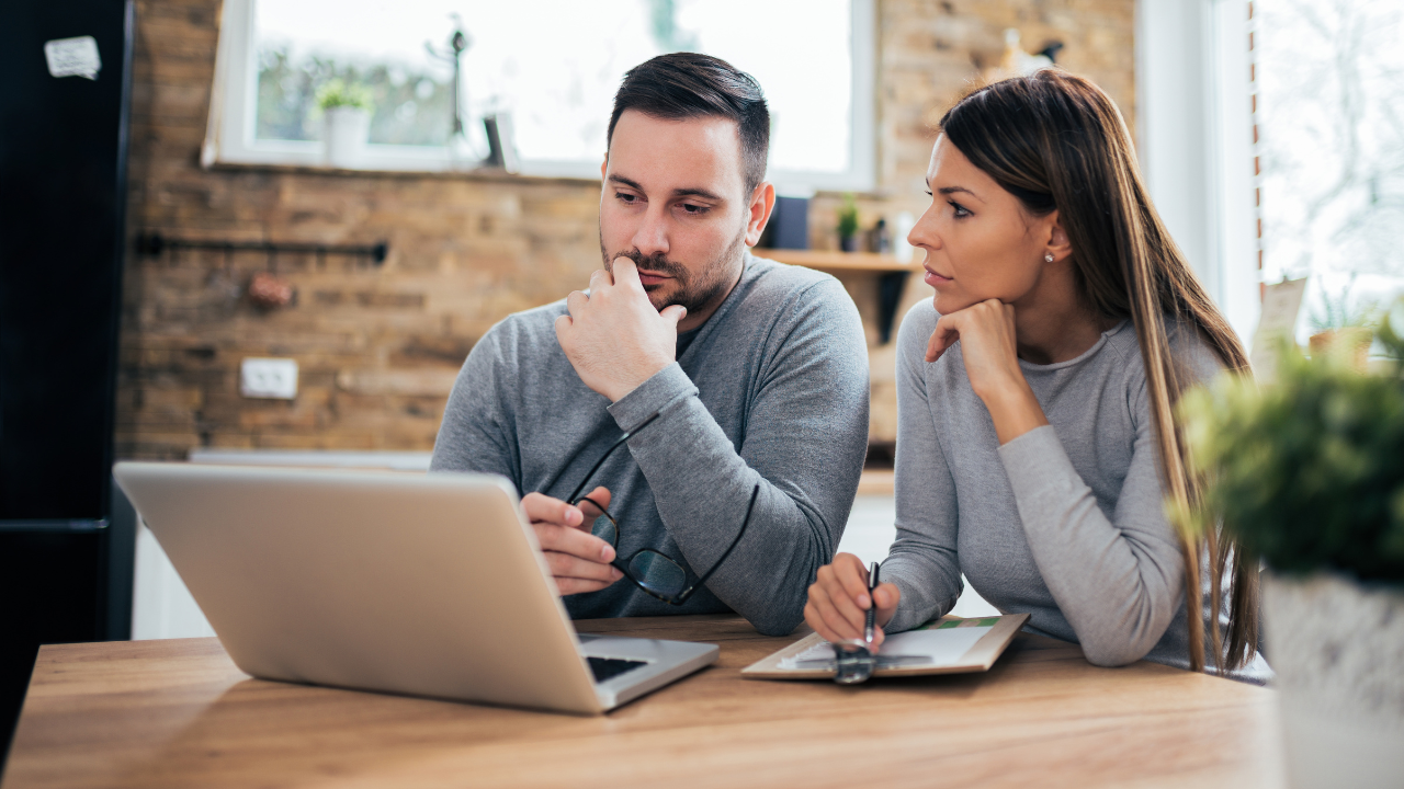 Couple sitting together reviewing laptop screen
