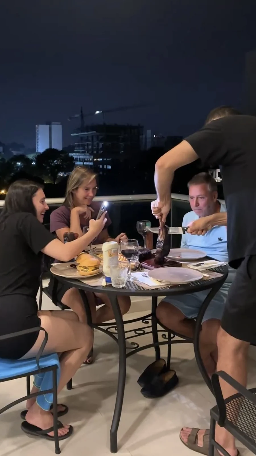 Kyra at a rooftop dinner table with her family at night