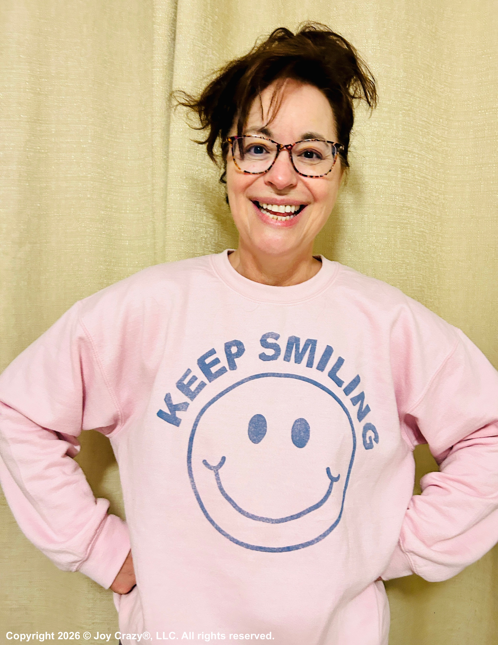 Shannon Paul Shannon Paul Smiles while wearing a pink sweatshirt that says "KEEP SMILING "