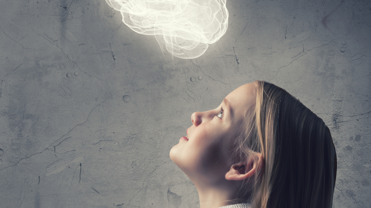 Niña observando una ilustración luminosa de un cerebro, representando el desarrollo neuronal y el aprendizaje infantil