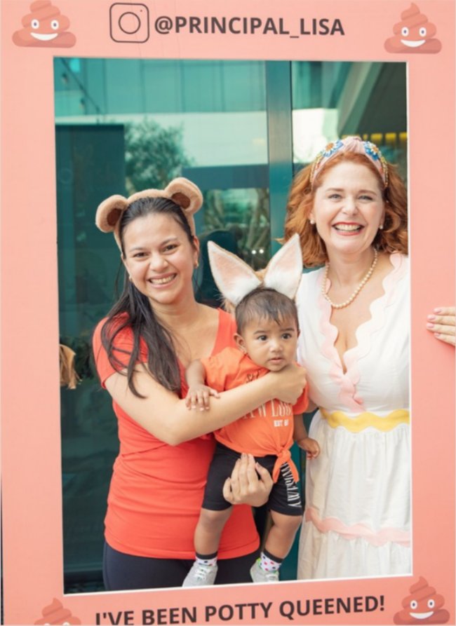 Lisa with a happy mum and toddler in the 'I've been Potty Queened!' photo frame