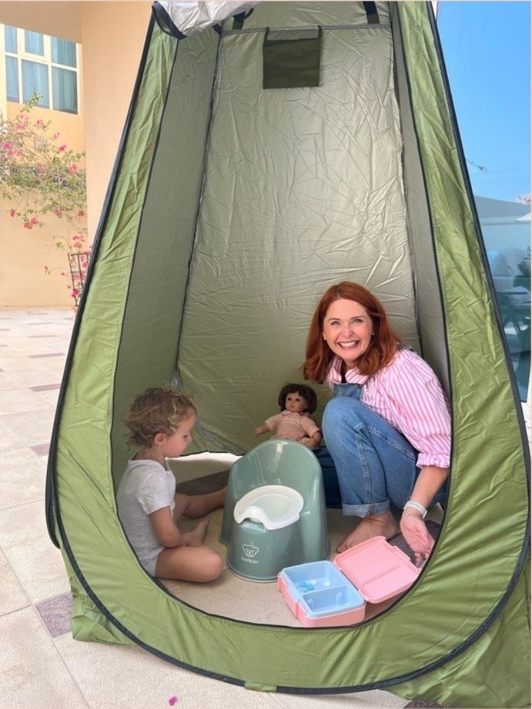 Lisa in a pop-up potty tent with a toddler during a home visit in the UAE