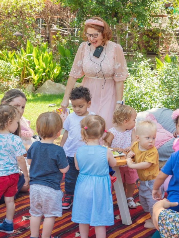 Principal Lisa reading with young children in a garden