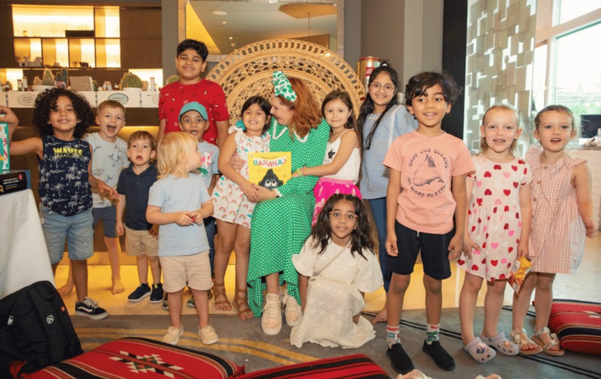 Principal Lisa holding a book with children gathered around her