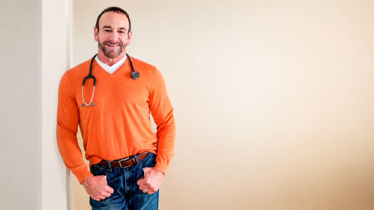 Professional portrait of Dr. Stephen Petteruti wearing an orange sweater and stethoscope, representing personalized healthcare at Intellectual Medicine