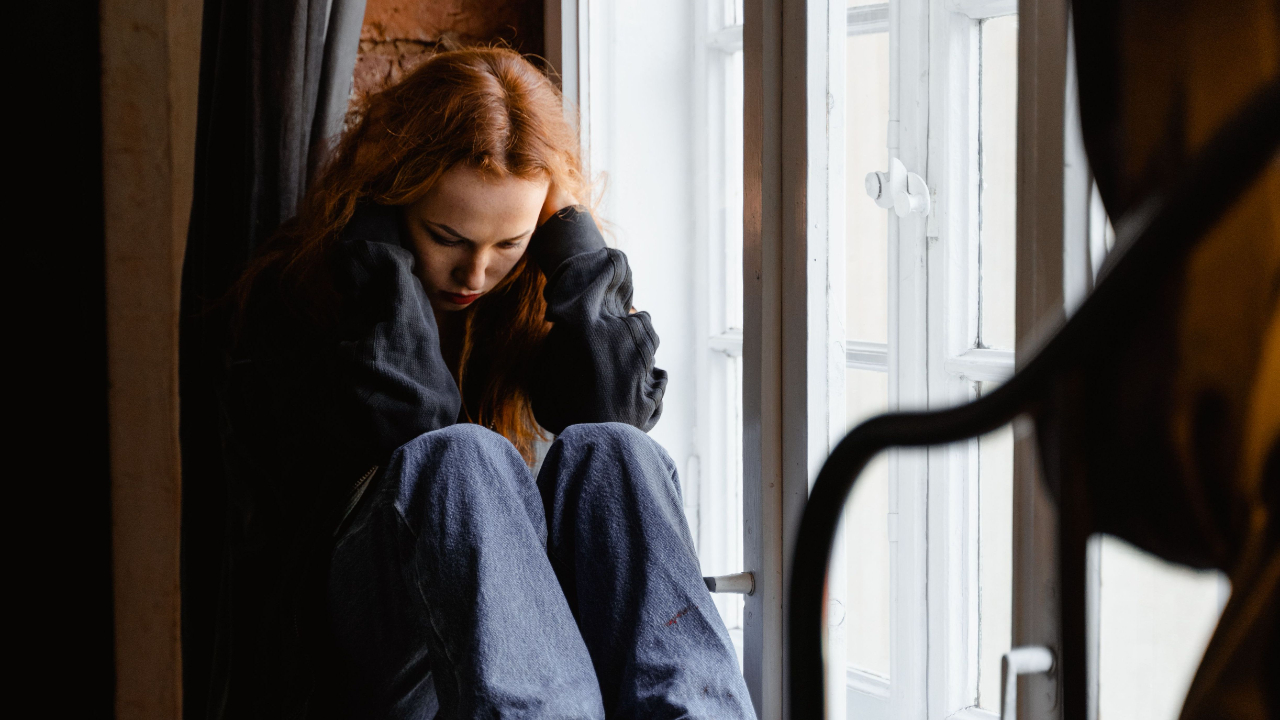 Woman sitting thoughtfully by a window, reflecting on whether her relationship feels healthy, safe, and emotionally clear.