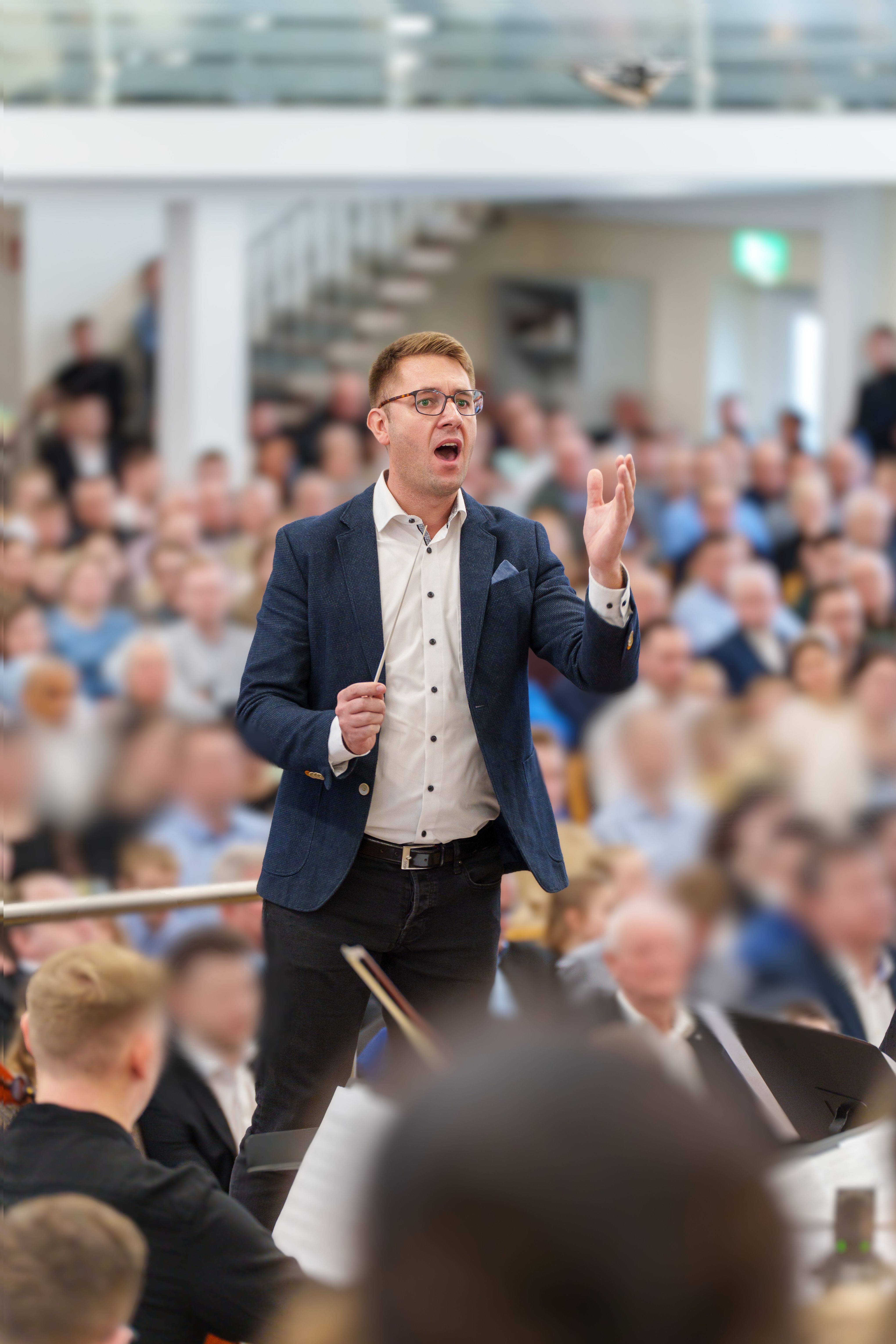 Marc Markus Pazer dirigiert vor Publikum und Orchester