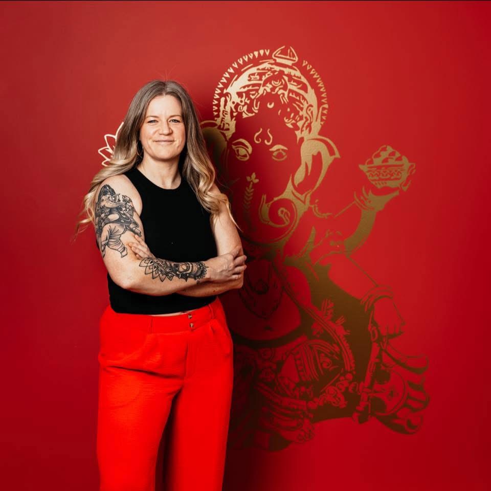 Heather Petrosky, yoga business coach and founder of We Be Yoga, standing with her arms crossed in her studio