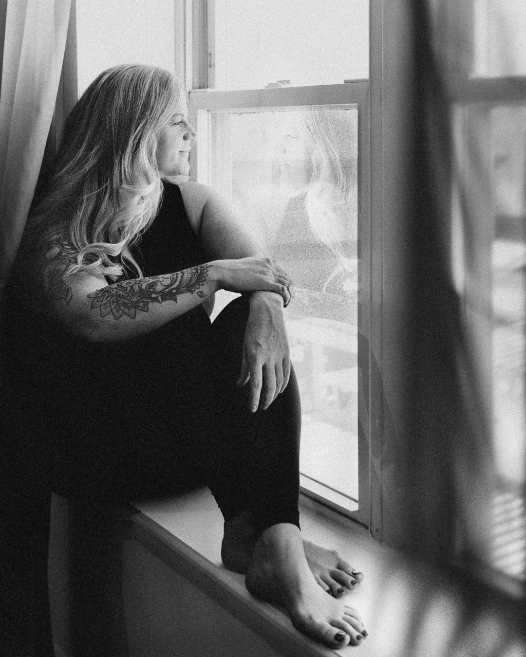 Heather Petrosky sitting in a studio window, looking out