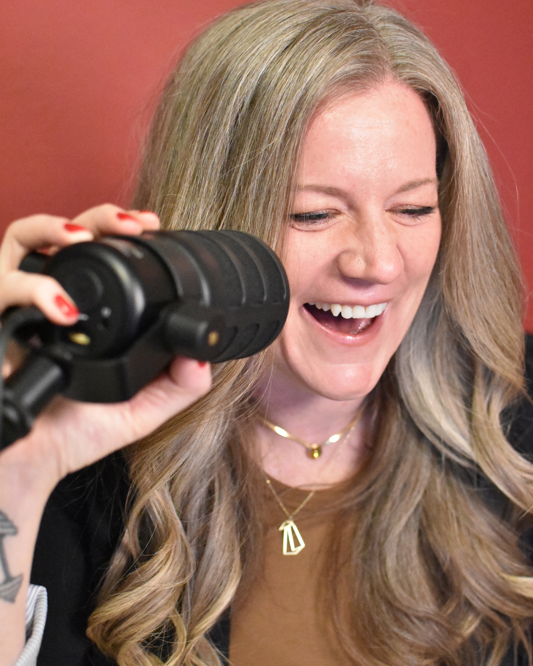 Heather Petrosky laughing while recording into a podcast microphone