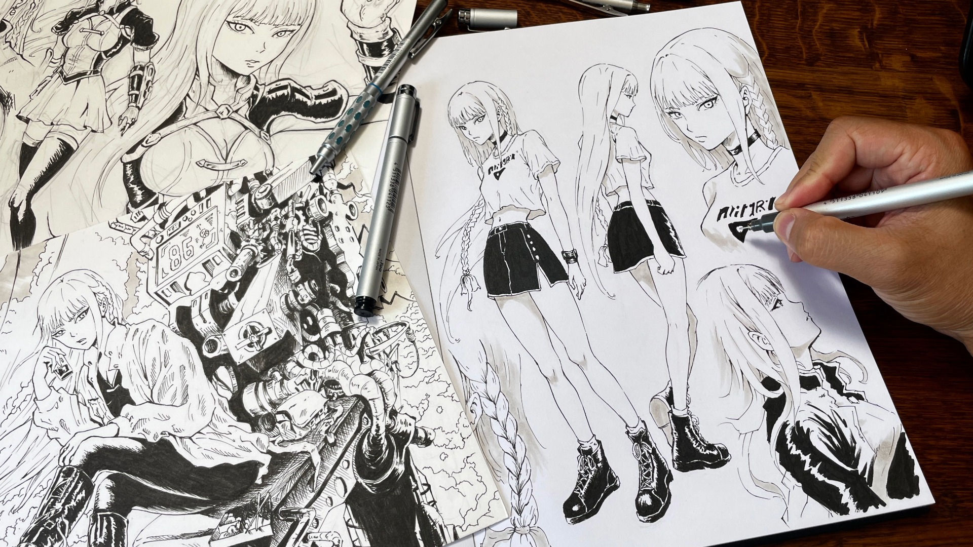 Une main encre à la plume une planche de manga posée sur un bureau en bois, montrant plusieurs personnages féminins dessinés en noir et blanc.