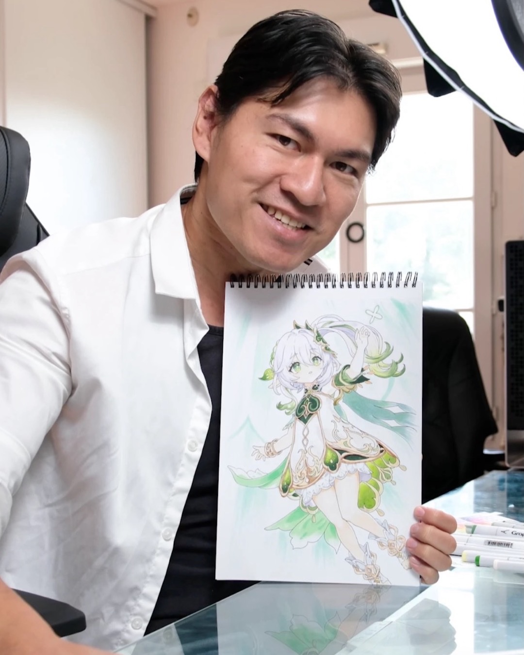 Wei tenant un dessin coloré d’un personnage type fée