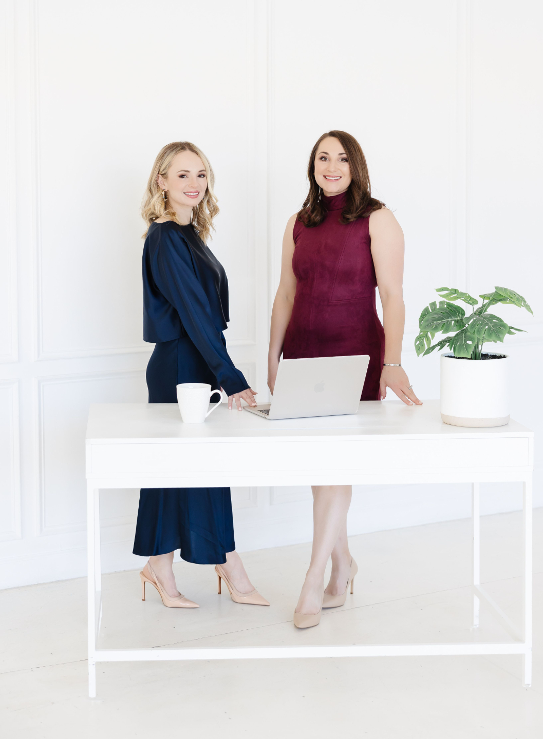 Casey and Nicole standing behind a desk, smiling at the viewer