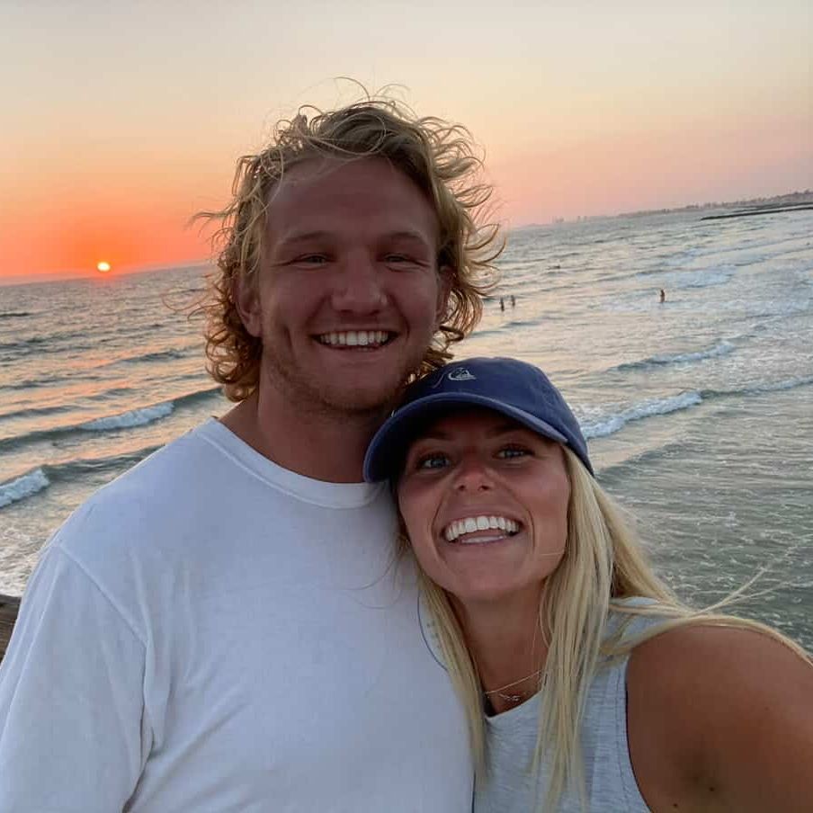 a man and woman are smiling in front of the ocean