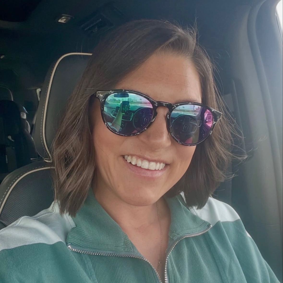 a woman is smiling in the front seat of a car.