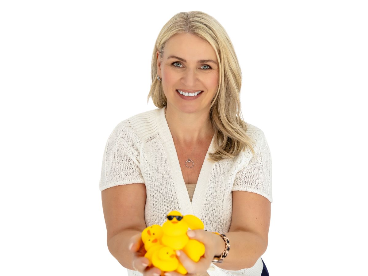 Dr Amanda Mullin smiling and holding out a handful of yellow rubber ducks