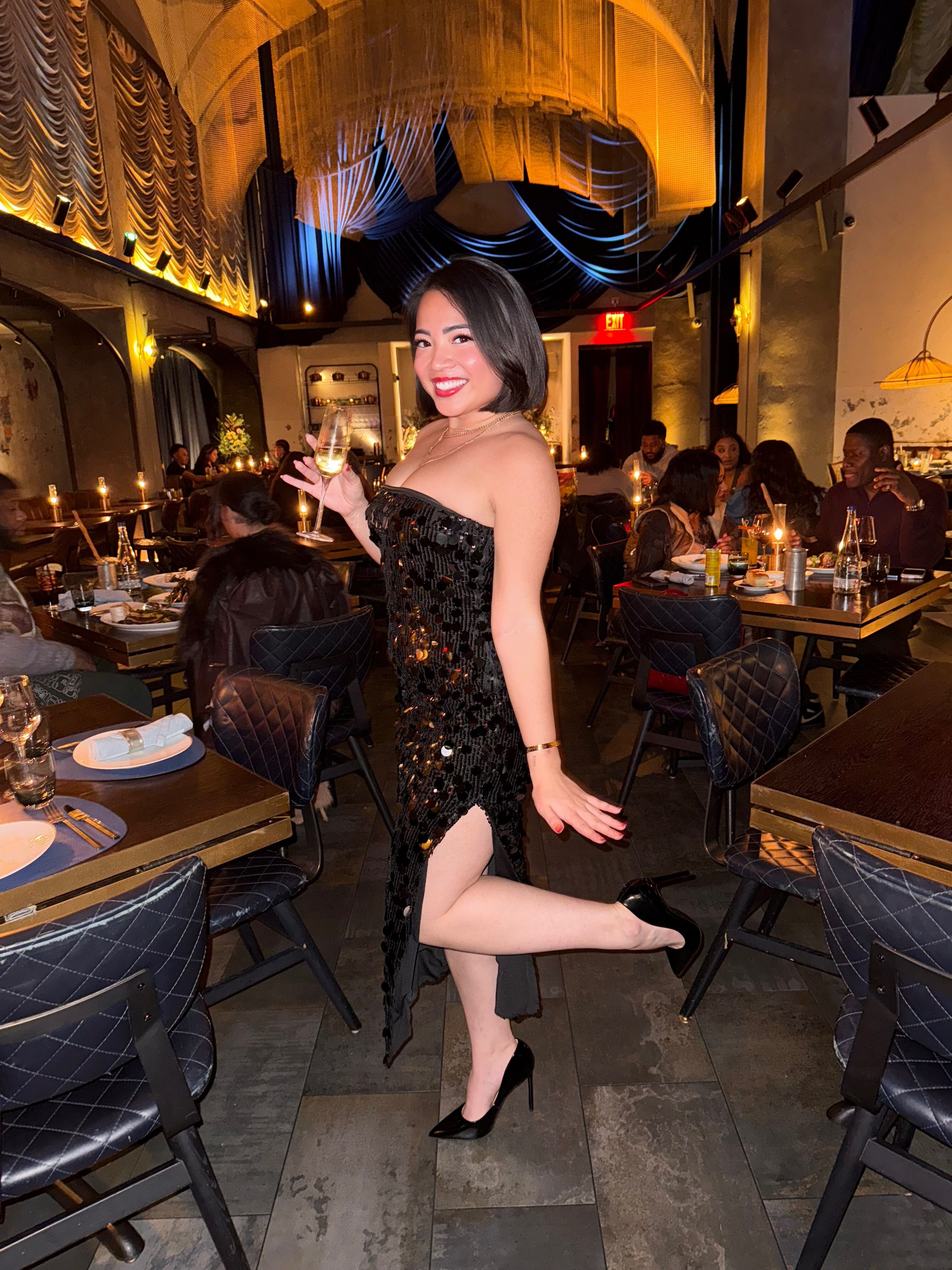 Megan in a black dress in a candlelit dining room