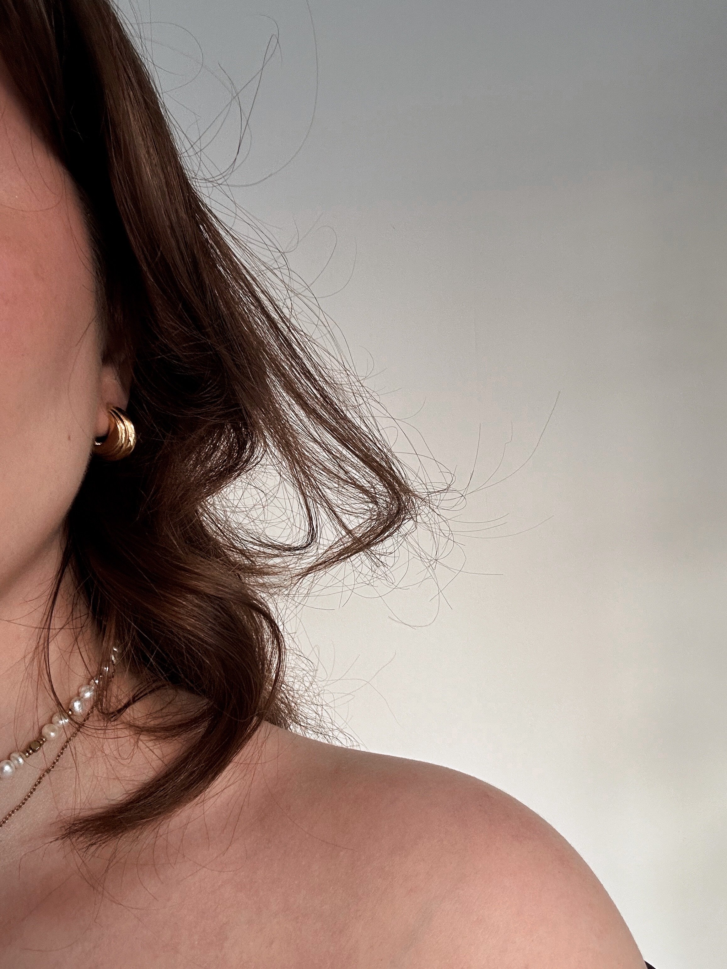 Gold earring and dark hair