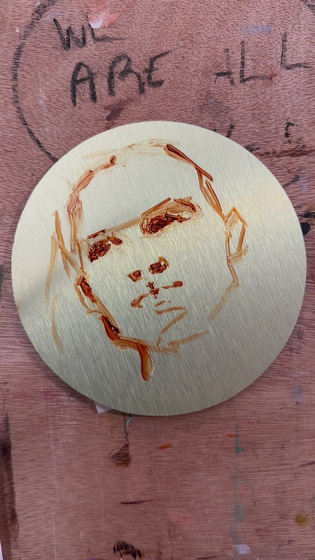 A thin earth-tone sketch of a face on the bare aluminium panel