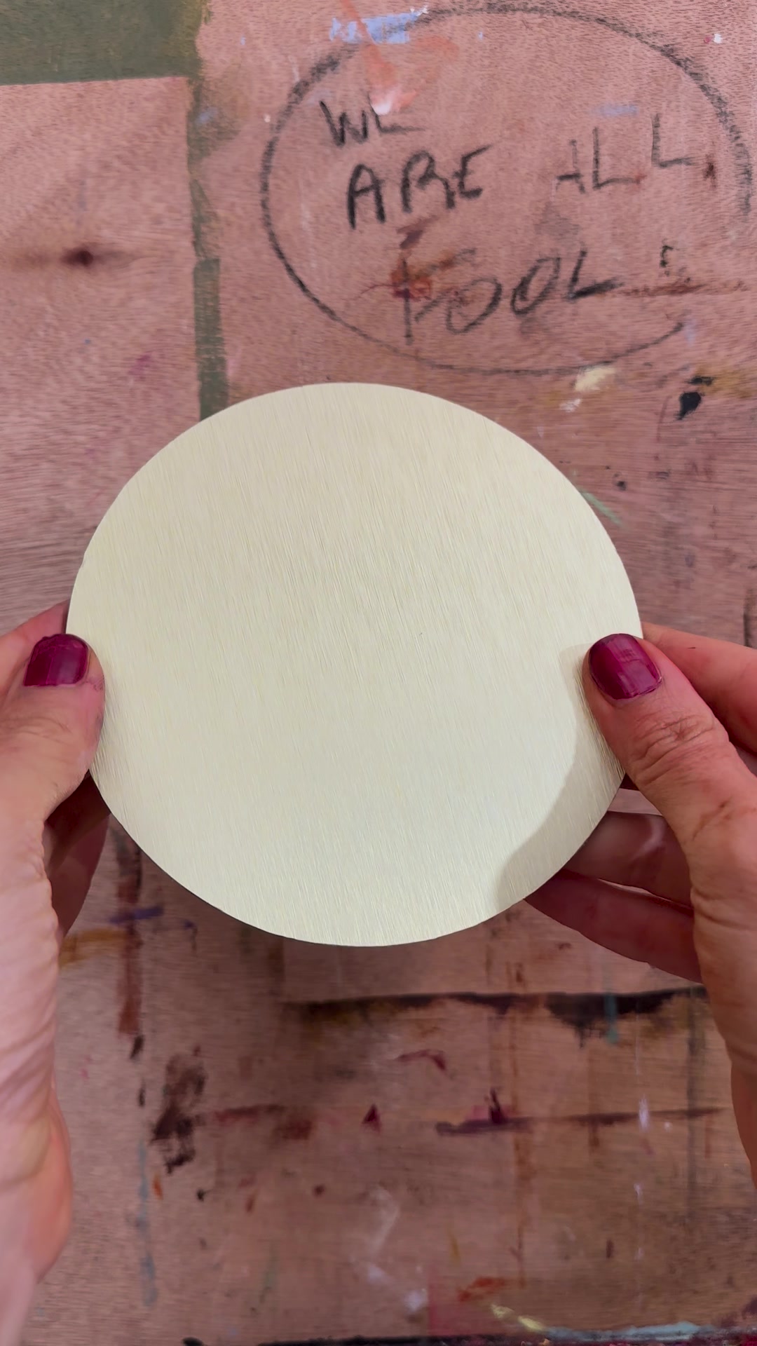 A round aluminium panel held in two hands, after the protective film is peeled off