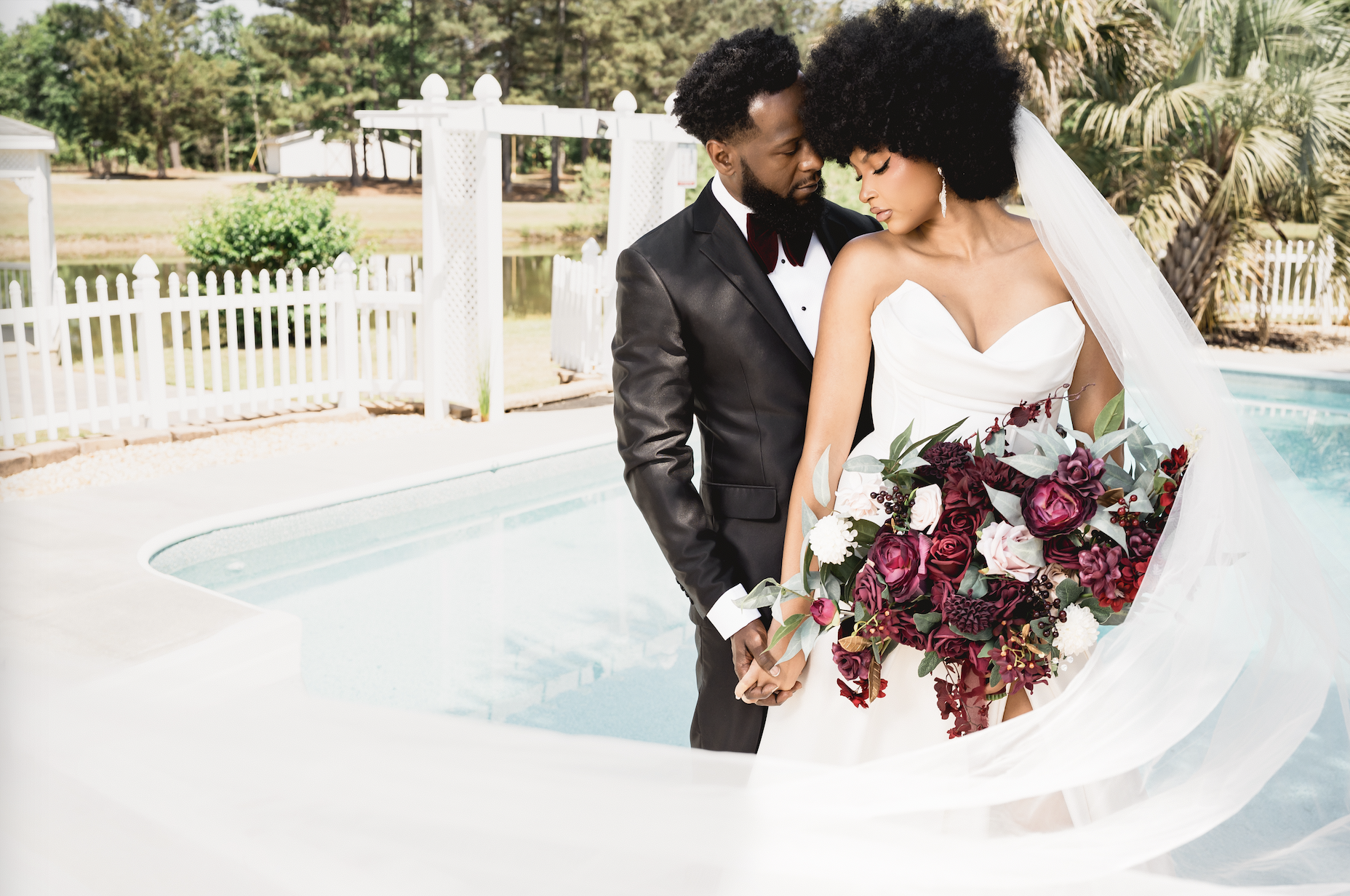 Poolside daytime wedding couple with a burgundy bouquet