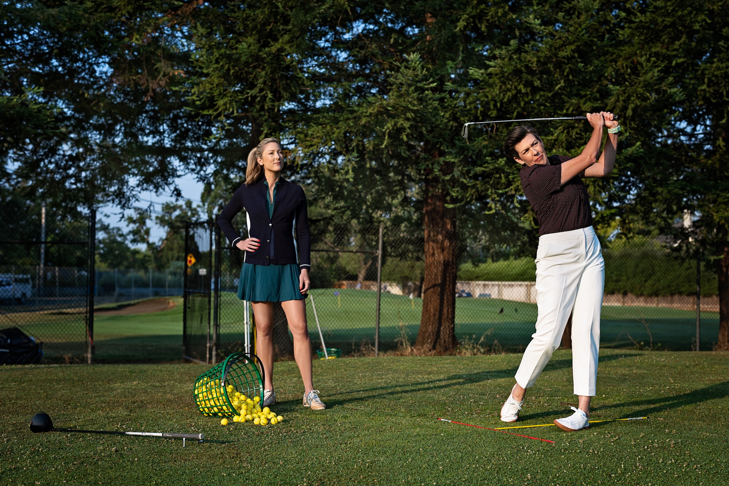 Amanda demonstrating an iron swing with a golfer observing
