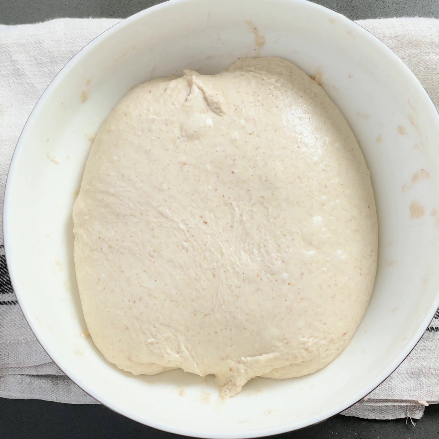 Smooth, risen sourdough dough in a white bowl