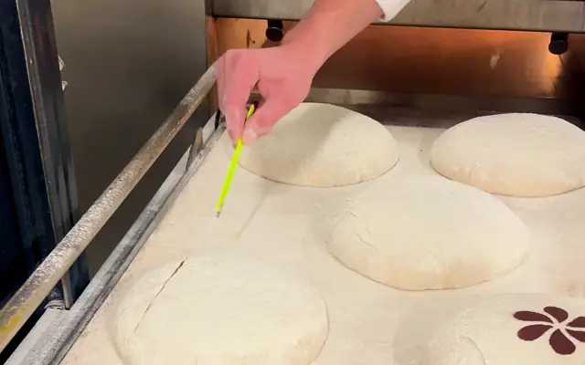 Scoring sourdough loaves by hand before baking, in France