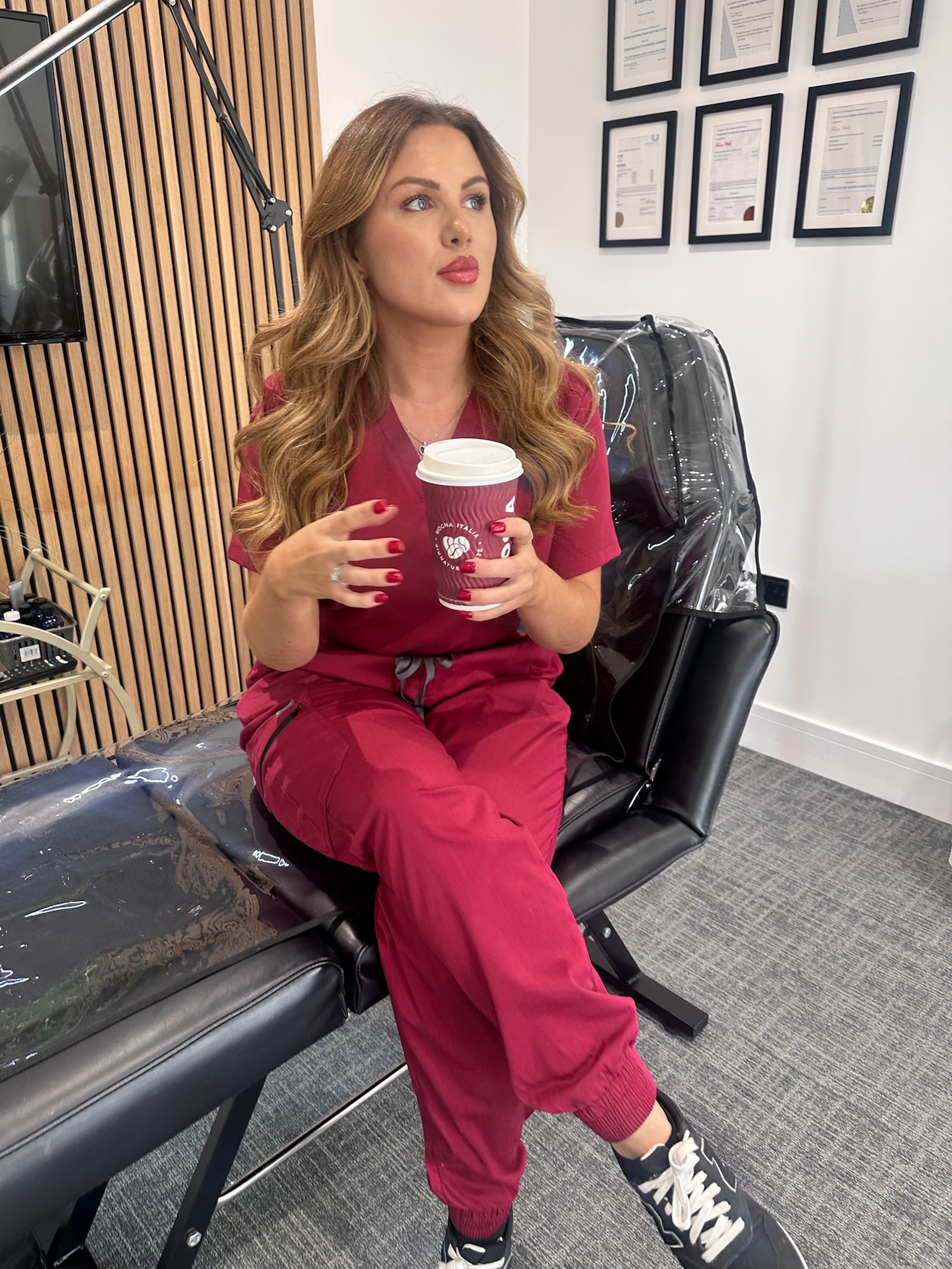 Fiona in her clinic treatment room in front of her training certificates