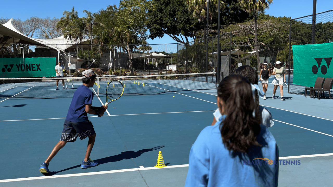 Teen tennis coaching session on a blue court at Ready For Tennis, Gold Coast, with players practising rallies and drills in a relaxed group environment