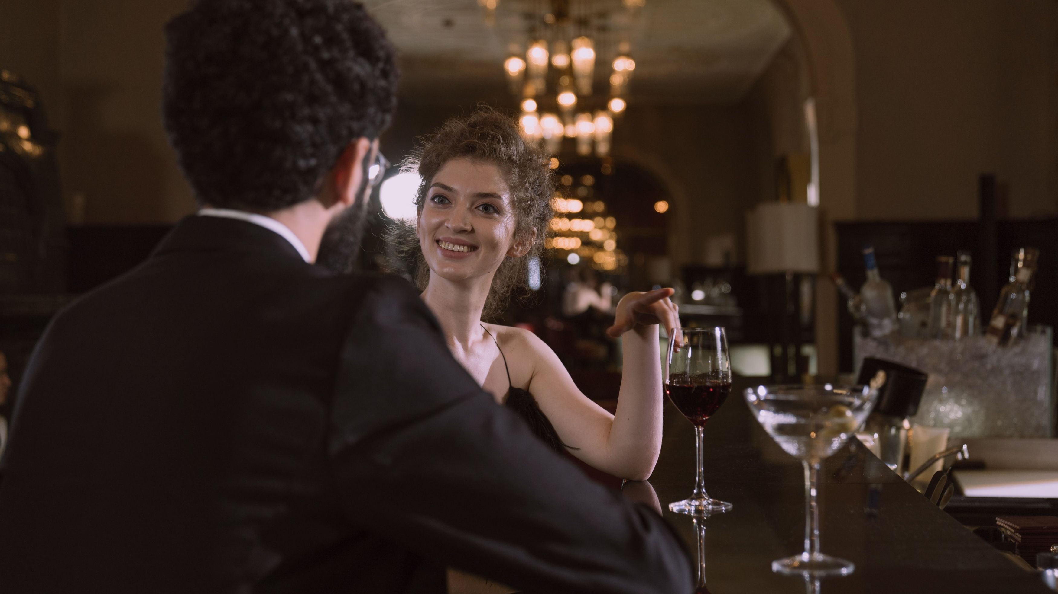 Sophisticated couple enjoys an intimate evening with red wine and cocktails at an upscale bar.
