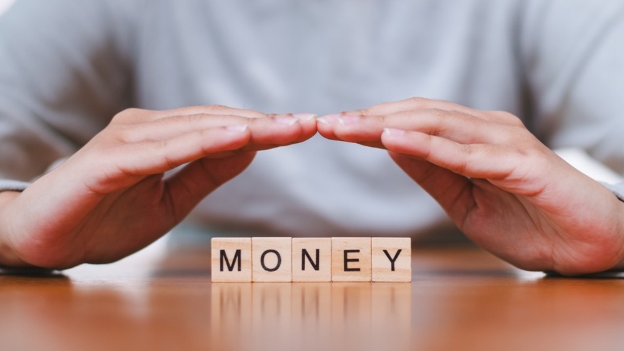 Hands helds over a money sign to represent wealth mindset