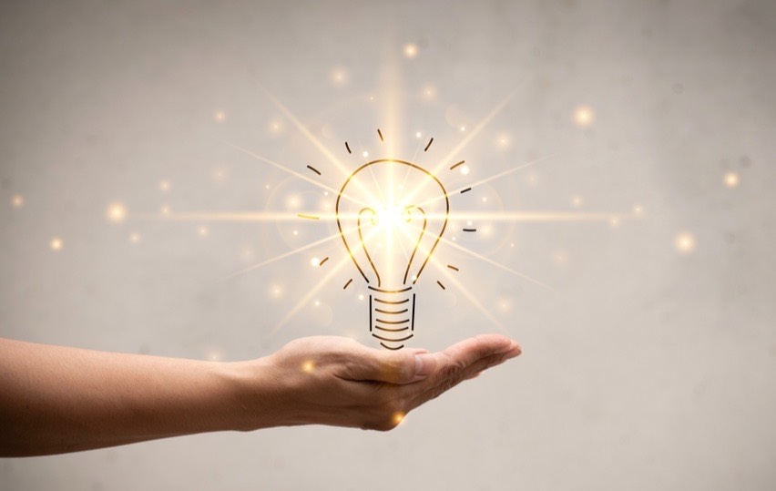 A hand holding out a bright and beautiful lightbulb