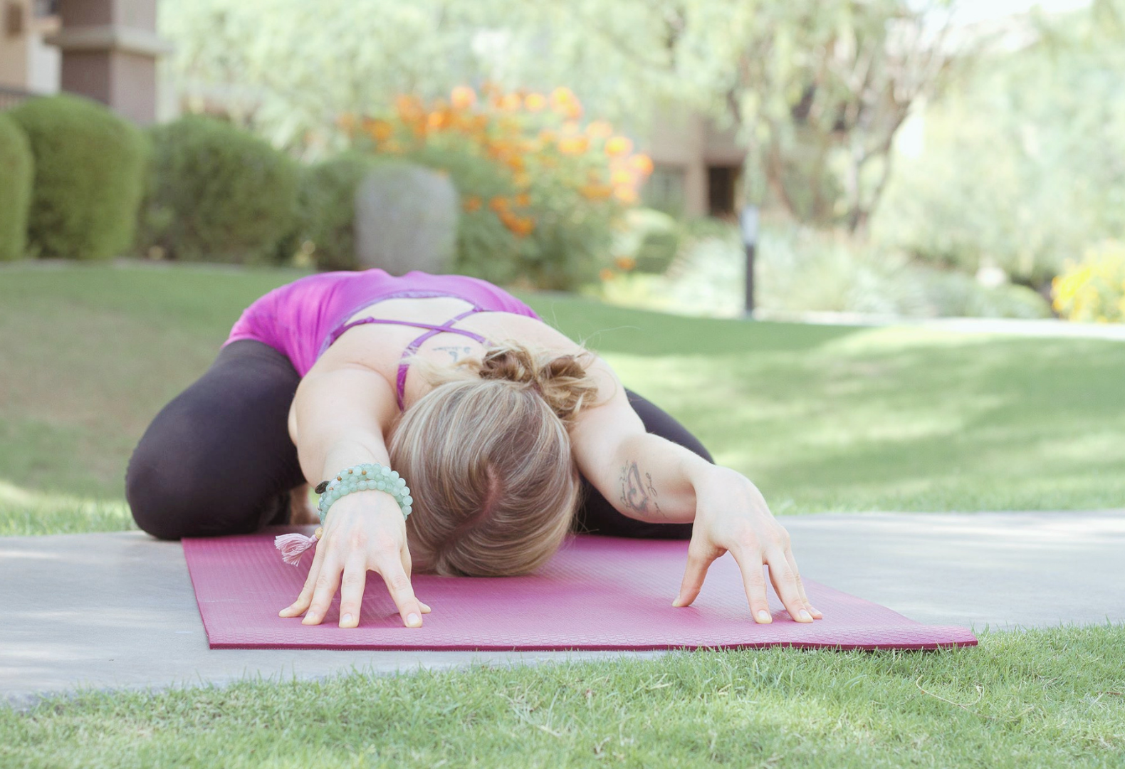 Yoga practitioner resting in a child's pose during a restorative mindful movement practice outdoors