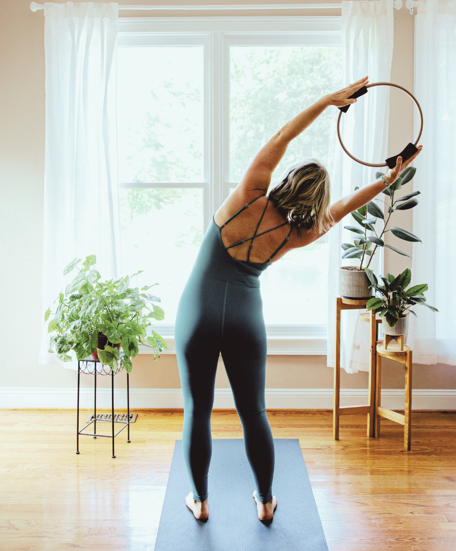 Barre instructor practicing mindful side bend movement with a Pilates ring during functional barre training